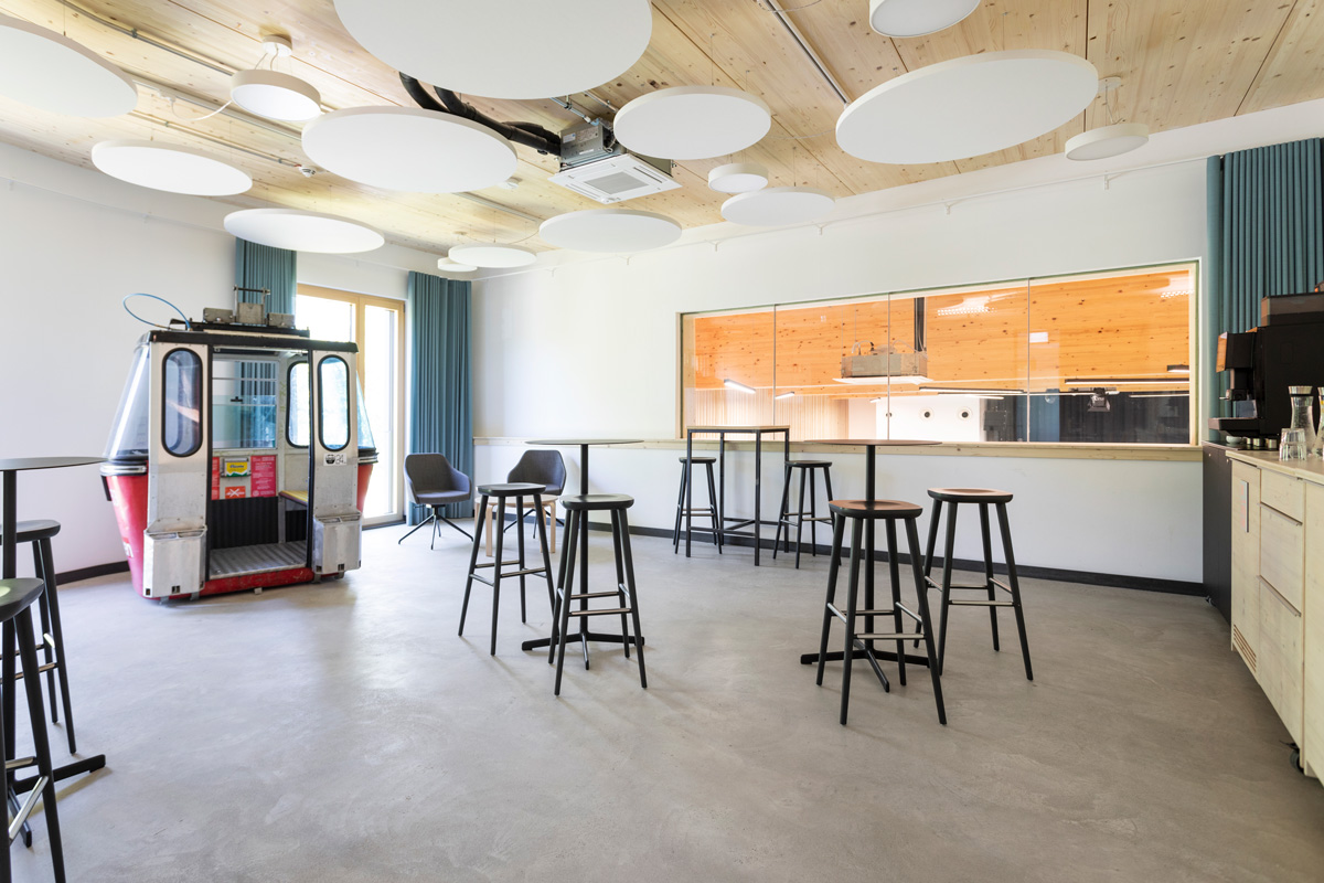 Pausenbereich Break area in front of the training room or classroom, featuring a lounge area with bar tables and stools