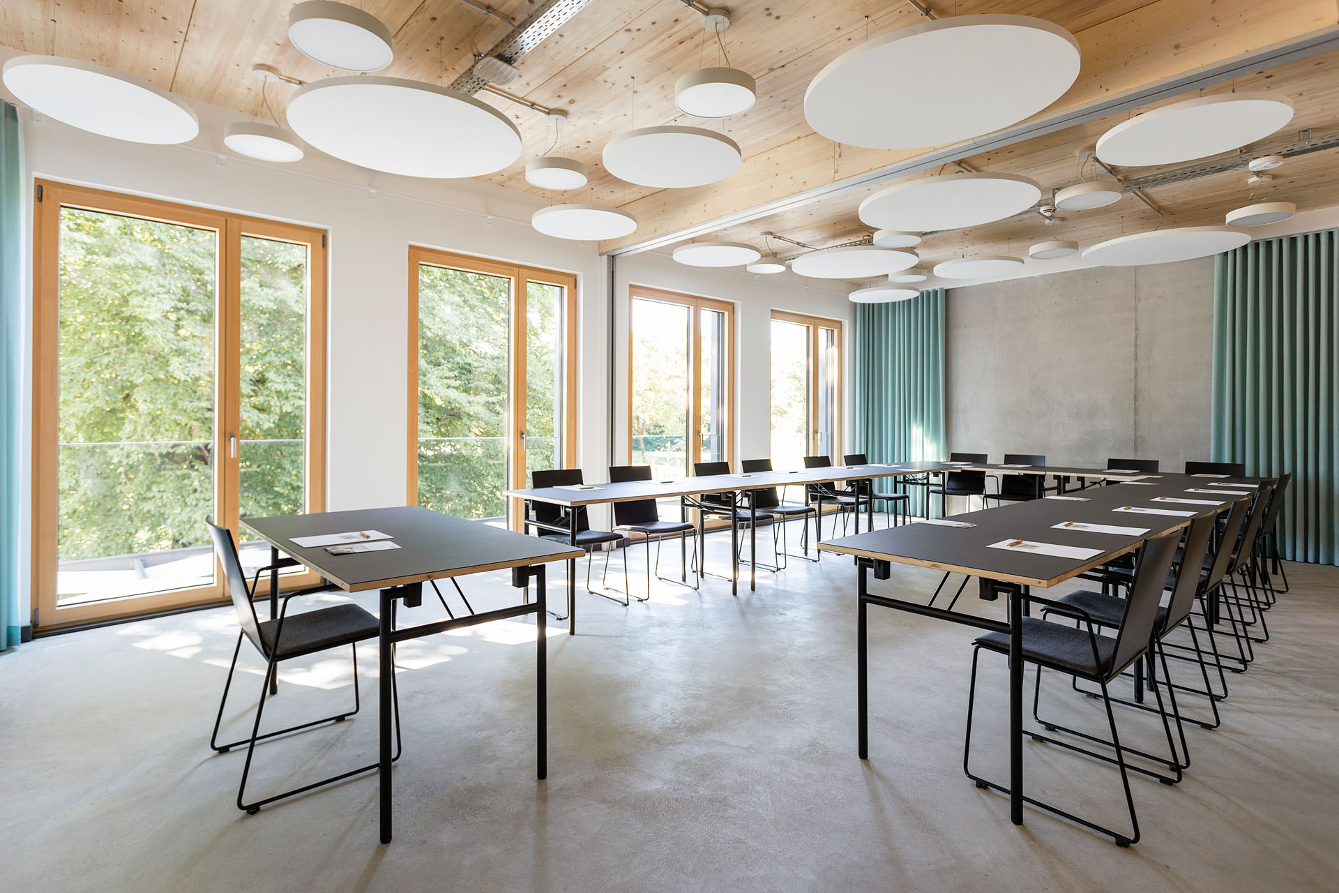 Kursraum „Alma“ Schrägansicht Front view of a classroom with U-shaped seating in front of large windows