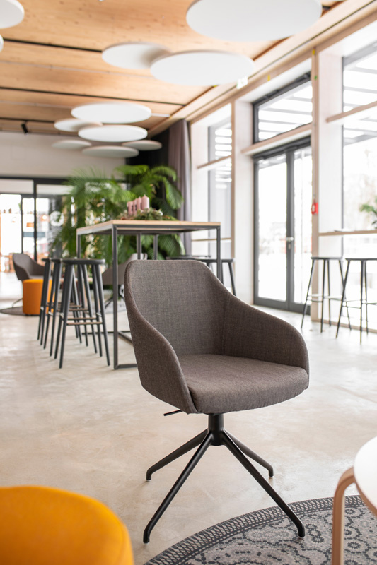 Drehsessel Foyer Gray swivel chair in a bright event venue with large windows