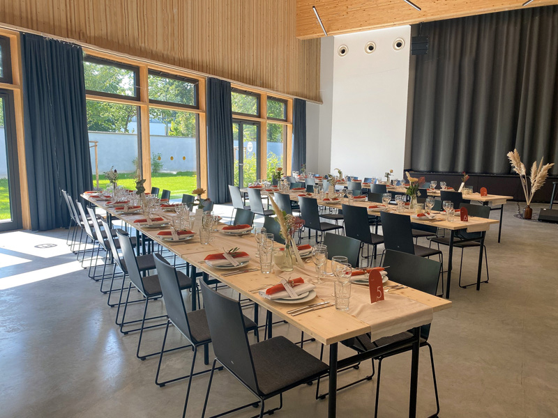 Saal Bankettbeispiel Saal zum Mieten mit gedeckten Tischen und großen Fenstern