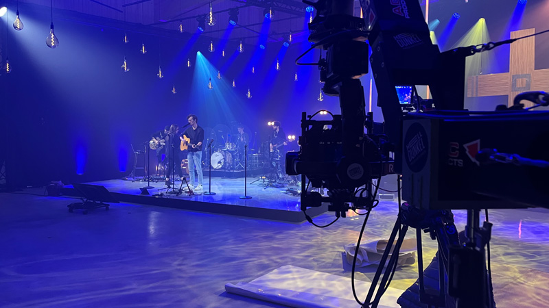 Saal Technikbeispiel Konferenz Saal zum Mieten mit Musikern auf einer Bühne in blauem Licht und einer Kamera