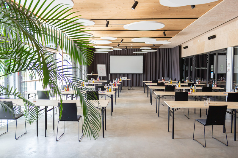 Foyer parlamentarisch Bright event venue with theater-style seating and plants