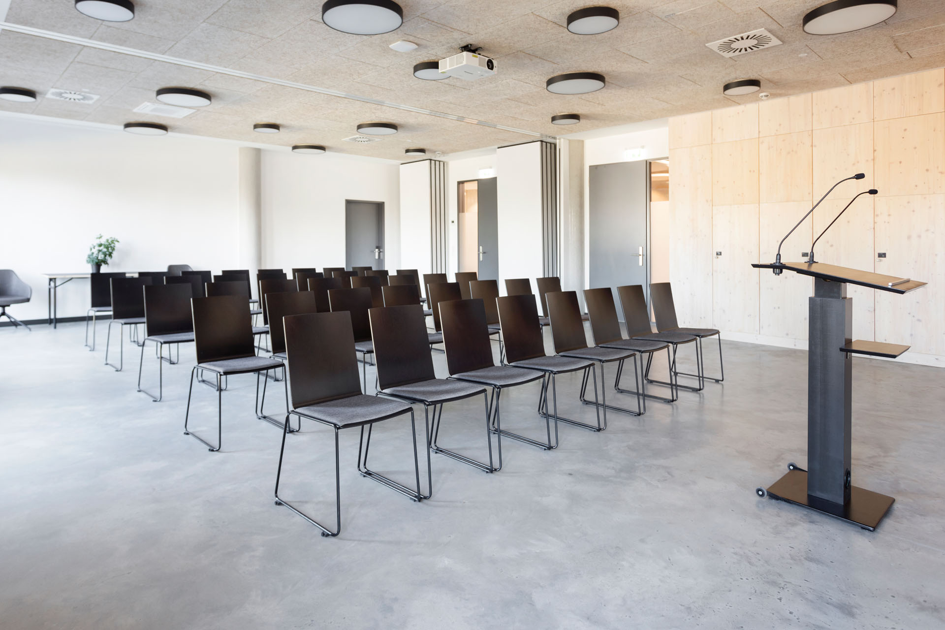 Konferenzraum zum Mieten mit schwarzen Stühlen und schwarzem Rednerpult