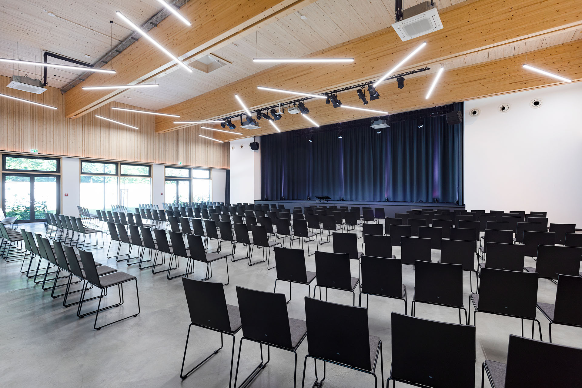 Saal zum Mieten mit schwarzen Stühlen und großer Bühne