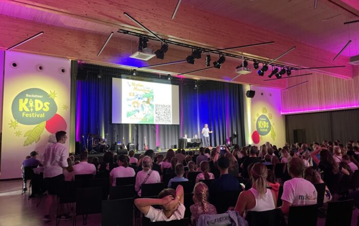 Veranstaltungssaal mit Kindern vor der Bühne bei einem Festival